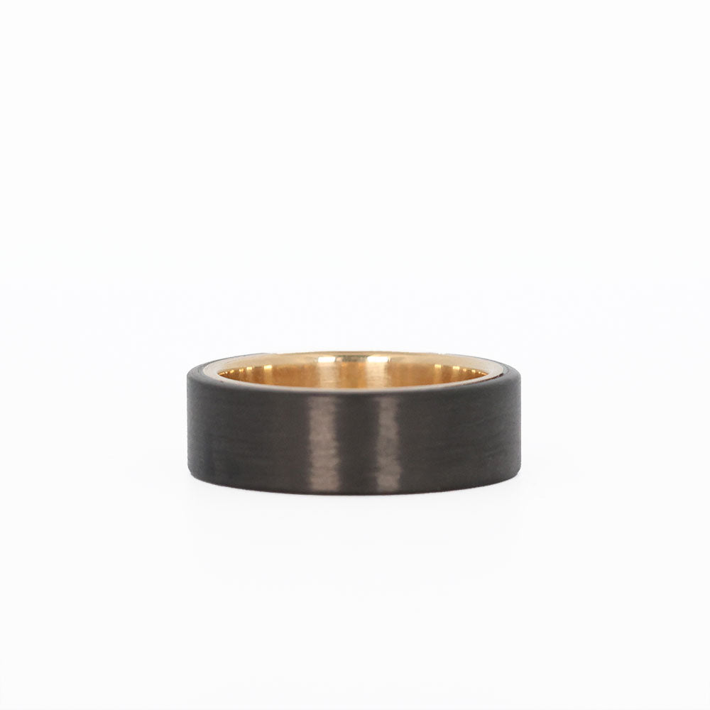 men's gold wedding ring with carbon fiber laying flat